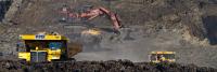 Dump trucks and cranes carrying and extracting coal from a coal work site.